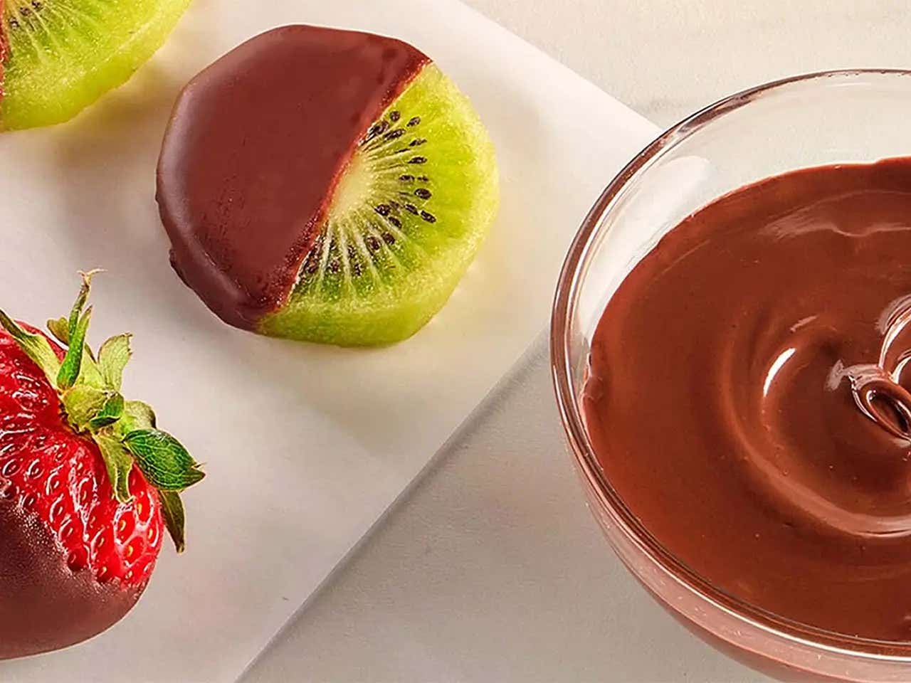 assortment of chocolate dipped fruits drying on wax paper