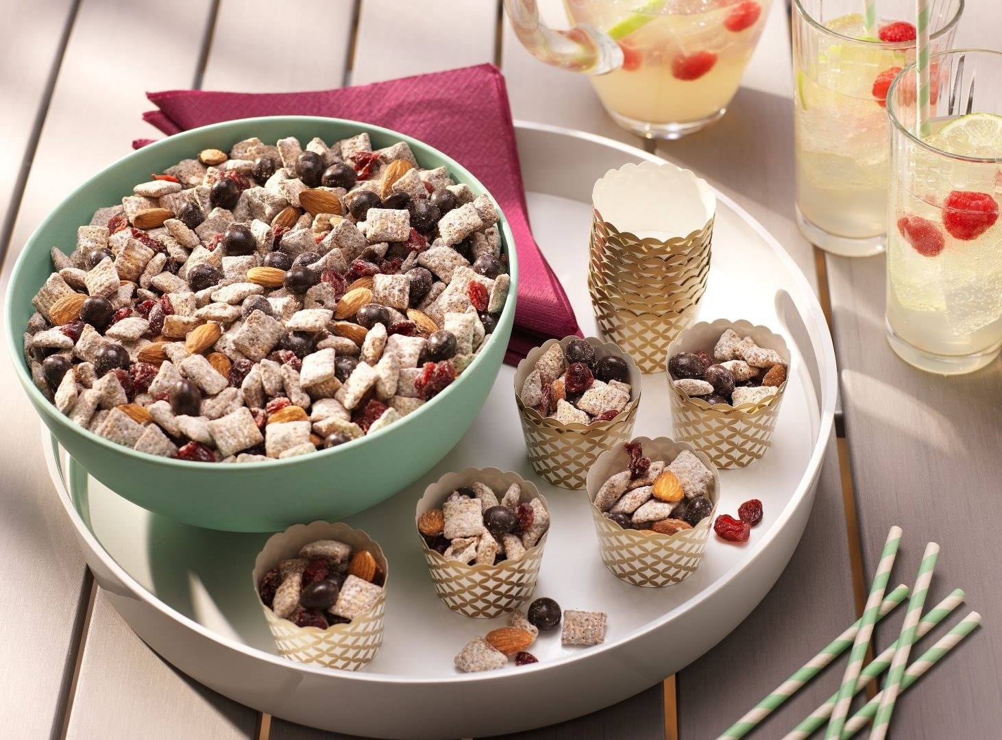 bowl of brookside party mix on an outside table with refreshing pitcher of a drink