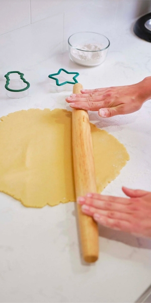 person rolling out cookie dough on the kitchen counter