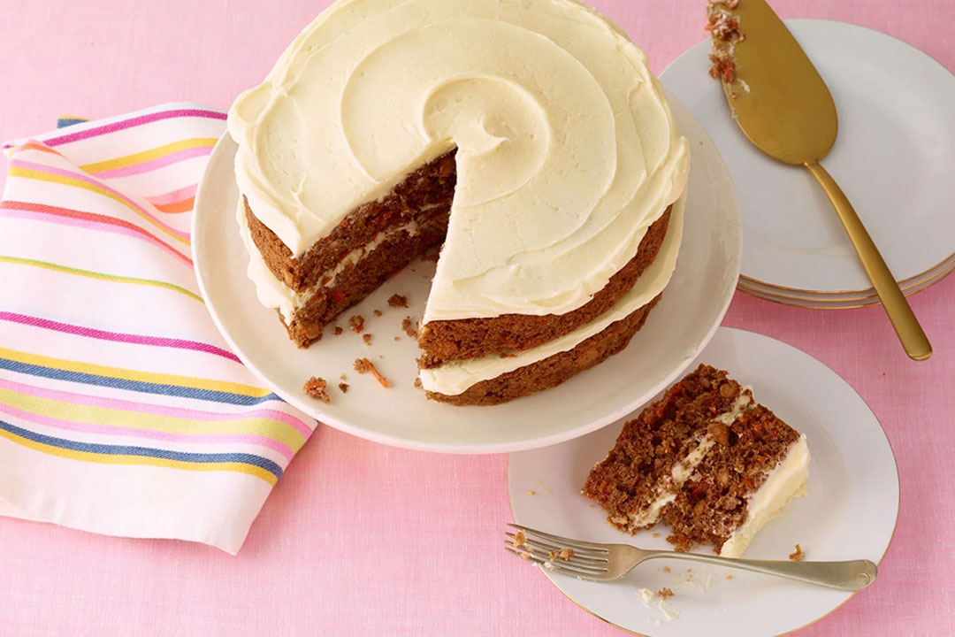 carrot cake topped with cream cheese frosting being sliced and served